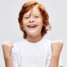 Cheerful redhead child white t-shirt smile Studio gray isolated background childhood